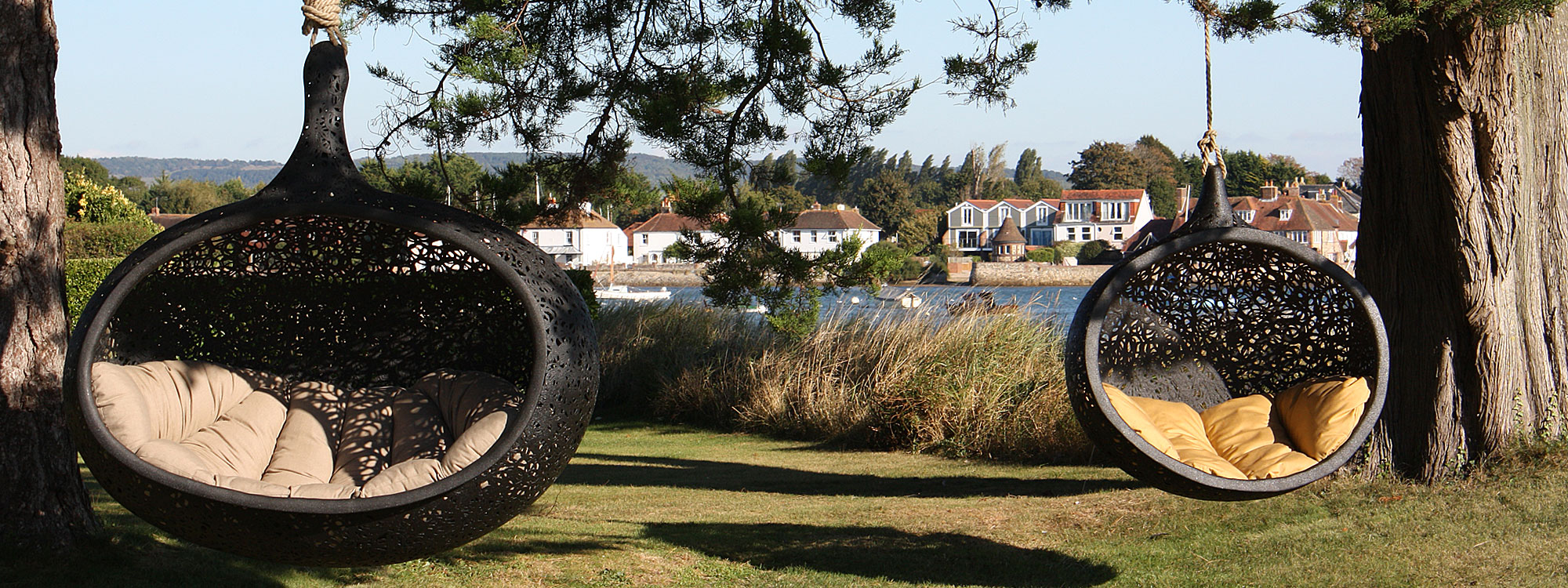 Image of Bios Hide & Bios Mini hung from cedar trees with Bosham harbor in background.