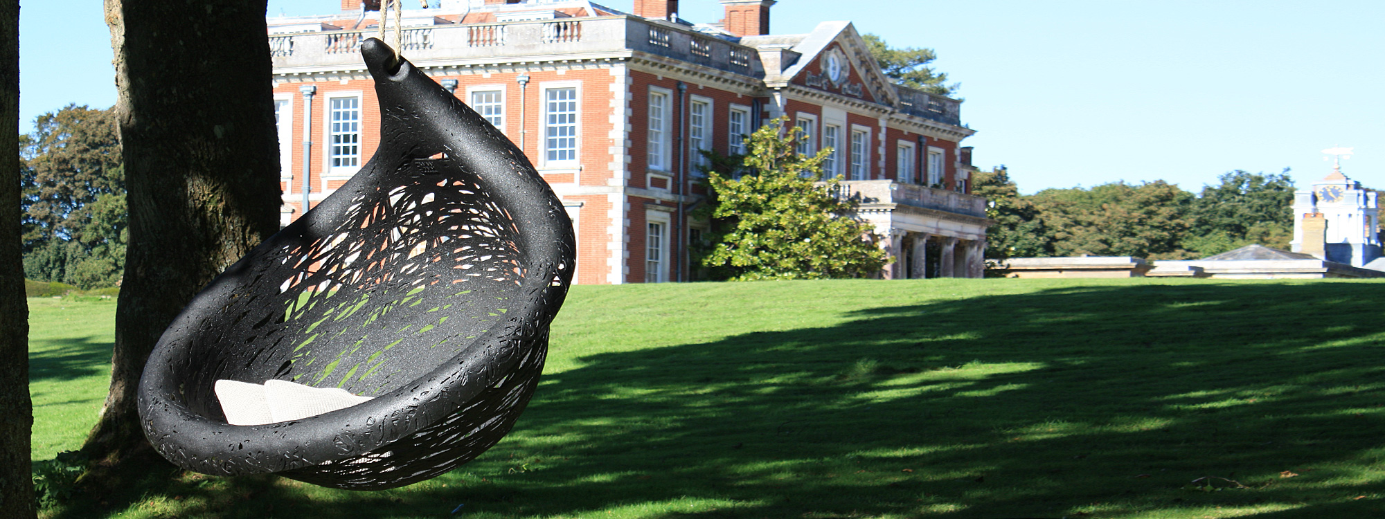 Image of Bios Lucid black swing chair by Unknown Nordic, with Stansted House stately home in the background