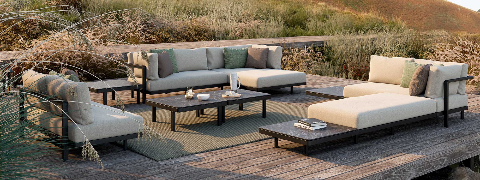 Image of pair of Alura Lounge modern outdoor corner sofas and 2 seater sofa by Royal Botania, on wooden decking surrounded by tall prairie grasses