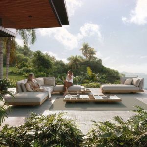 Image of pair of women sat on Royal Botania modern garden corner sofa with tropical planting and coastline in the background