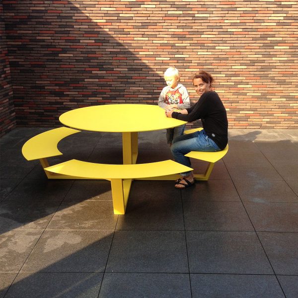 Mother & Son Sat At Yellow La Grand Ronde CIRCULAR PICNIC TABLE Is A Round STEEL Picnic Table In HIGH QUALITY Picnic Set Materials By Cassecroute DESIGNER Picnic FURNITURE. Grande Ronde Modern Round Picnic Table And Benches Seats 8-12, And Is Available In Any RAL Colour Of Your Choice.