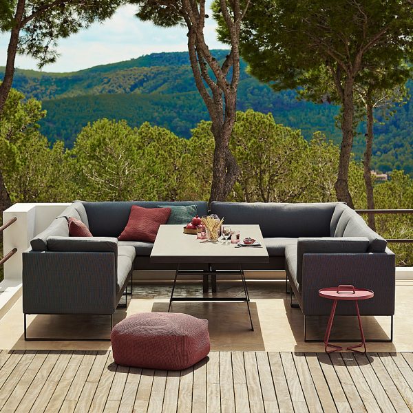 Image of Flex grey garden sofa around Cane-line dining table with trees and undulating hills in background