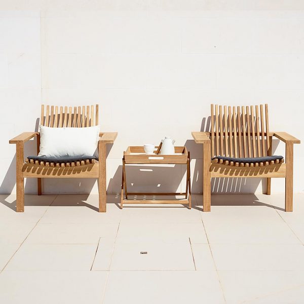 Image of pair of Amaze modern teak lounge chairs by Cane-line against sunny wall