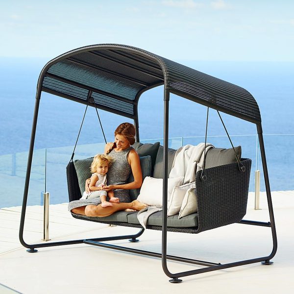 Image of mother and child sat in Caneline Cave modern sofa swing in black