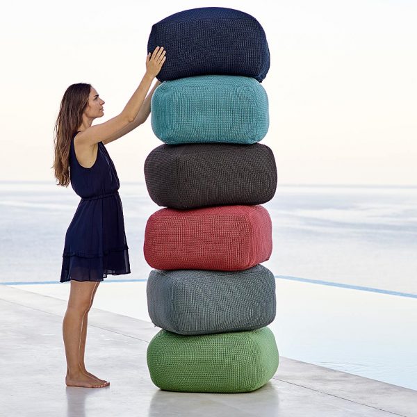 Image of stacked Caneline Divine poufs with woman about to remove the top one.