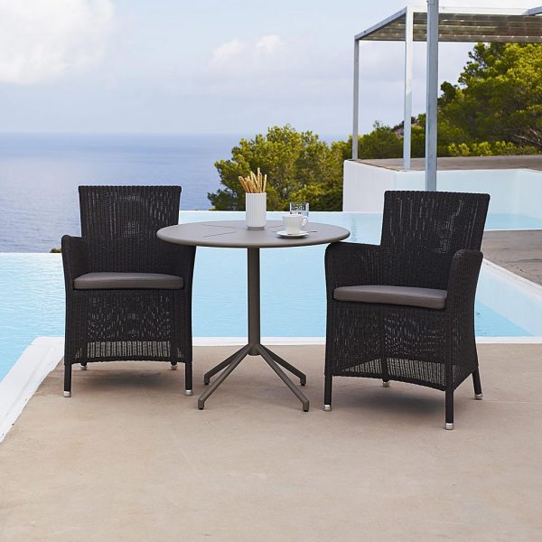 Image of pair of Hampsted black rattan garden chairs and small bistro table by Cane-line on poolside terrace