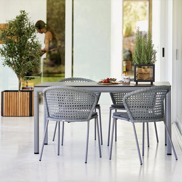 Image of Caneline Lean garden chairs in grey French weave, next to Droplight grey garden table