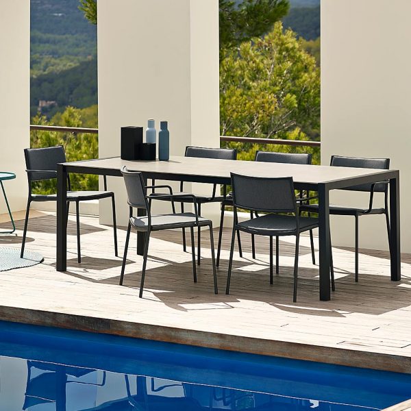 Image of dark-grey Less garden chairs around Cane-line dining table on sunny poolside