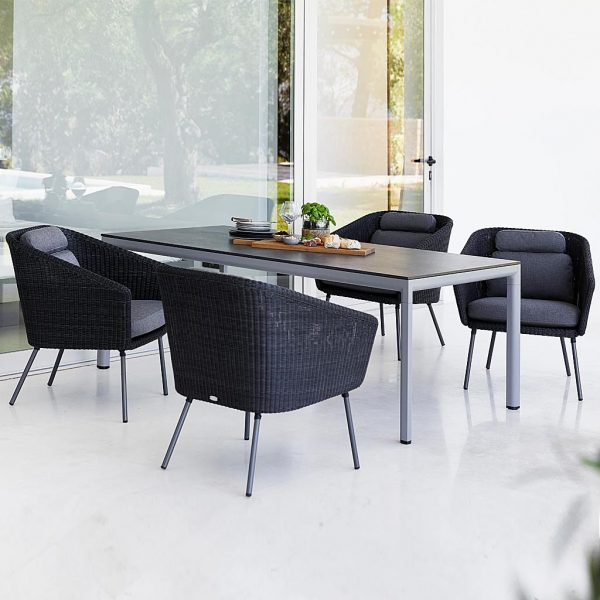 Image of 4 Mega black synthetic rattan chairs around Drop light-grey dining table by Cane-line