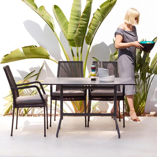 Image of black Cane-line Newport chairs on white terrace, with bird of paradise plant in the background
