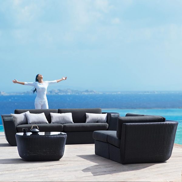 Image of woman throwing her hands in the air behind Savannah black garden sofa by Cane-line