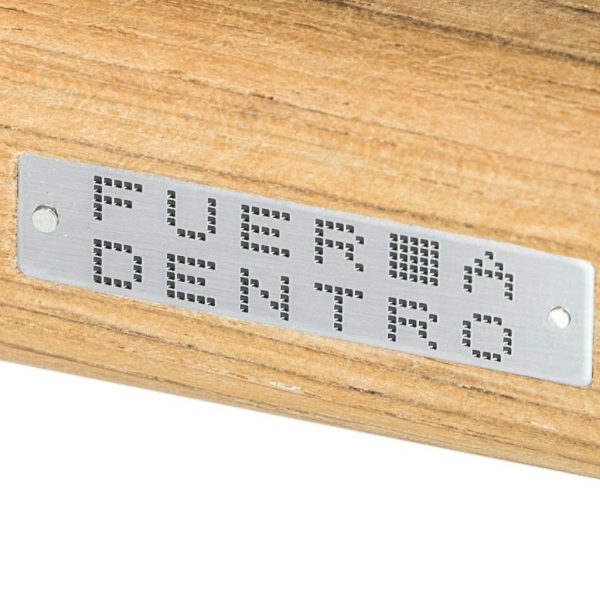 Image of detail of FueraDentro sun lounger's teak frame and stainless steel logo plate
