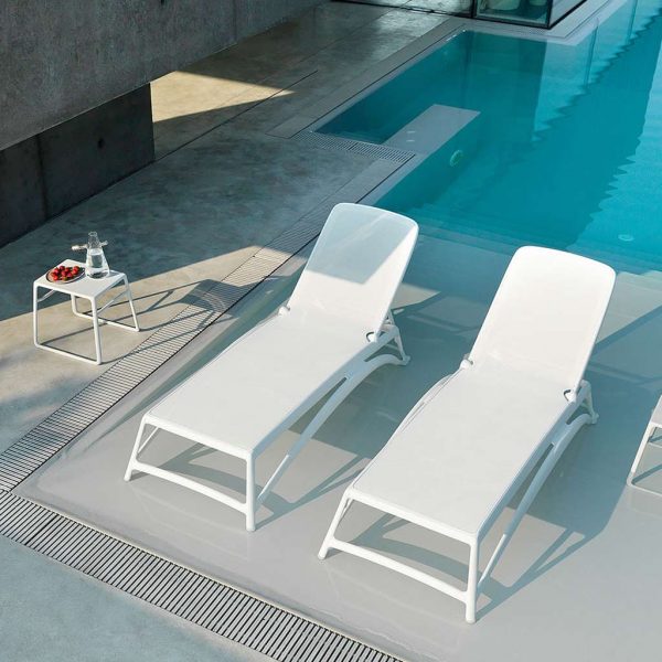 Image of aerial view of pair of Nardi Atlantico white contract sunbeds and Pop side tables, shown in sunny poolside