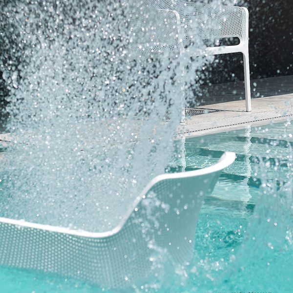 Image of Net white garden lounge chairs by Nardi, shown in and around swimming pool, being splashed with water