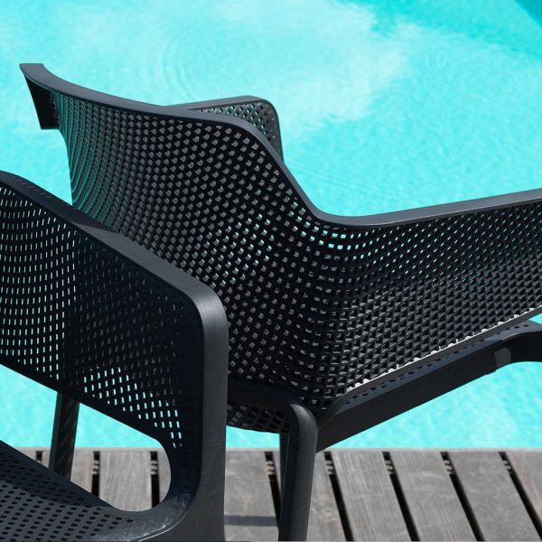 Image of detail of Nardi Net garden chair's perforated polypropylene back, with azure water of swimming pool in the background