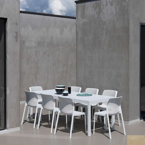 Image of Bit white outdoor chairs and Rio white outdoor dining table by Nardi, shown on grey polished concrete terrace