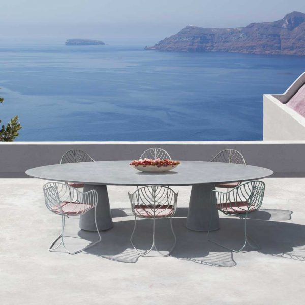 Image of Conix concrete table & white Folia chairs by Royal Botania luxury garden furniture, on whitewashed terrace over-looking shimmering Ionian sea