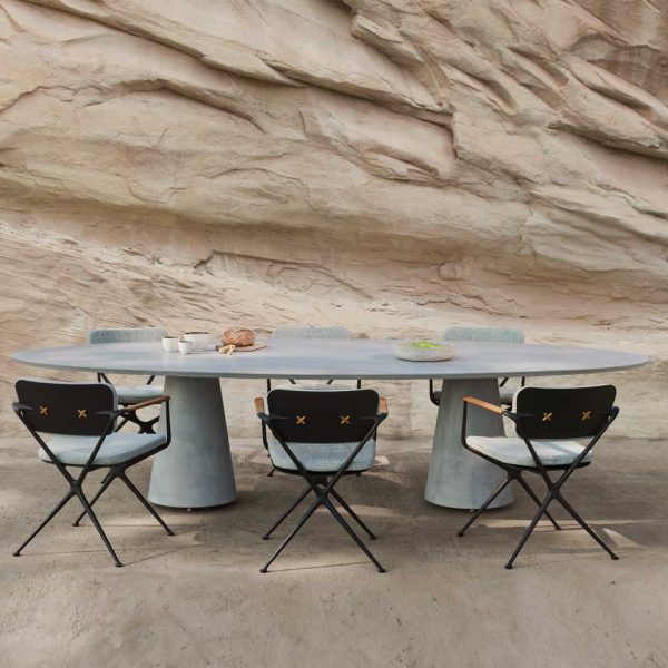 Image of Conix oval table and Exes chairs by Royal Botania with dramatic rocky background