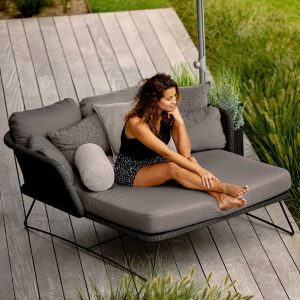 Woman relaxing on black Horizon chaise with grey cushions by Cane-line high quality garden furniture