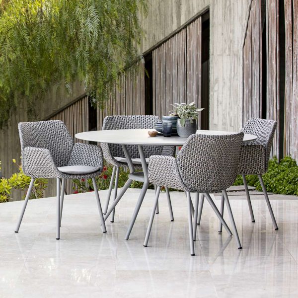 Image of poured concrete terrace with 4 Vibe rattan chairs and Joy round garden dining table by Cane-line