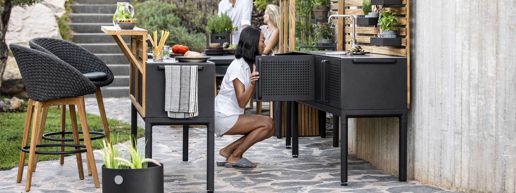 Image of pair of Caneline Peacock bar stools next to Drop outdoor kitchen island