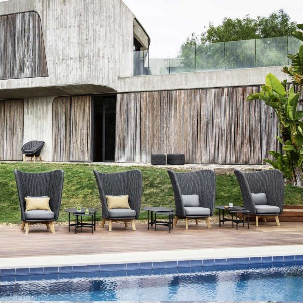 Image of row of 4 Peacock Wing high backed lounge chairs and Twist low tables by Caneline, along poolside