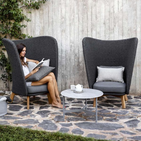 Image of woman sat reading in Peacock Wing black garden lounge chair by Cane-line