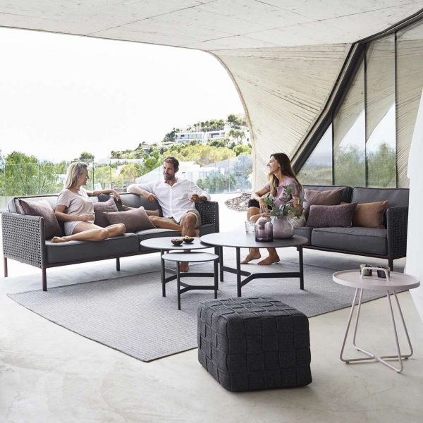 Image of 3 people relaxing in Encore woven garden sofas with nest of Twist circular coffee tables by Cane-line