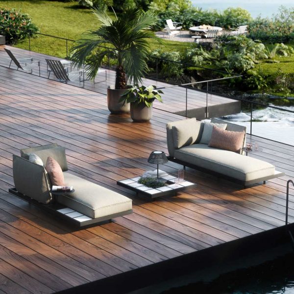 Image of Mozaix Alu minimalist outdoor daybeds by Royal Botania on wooden decking, with exotic plants and lawn in the background