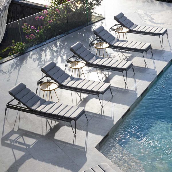 Image of row of 5 Cane-line Breeze sun beds and On The Move side tables, shown in sunny modern poolside