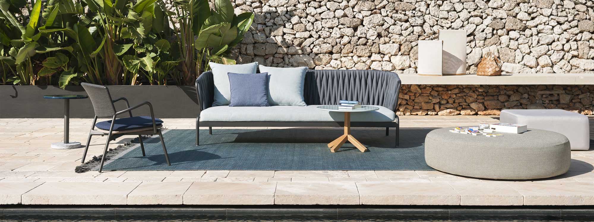 Image of RODA Spool 3 seater garden sofa with grey padded belt back and light-grey cushions, shown with Root side able and Double pouf
