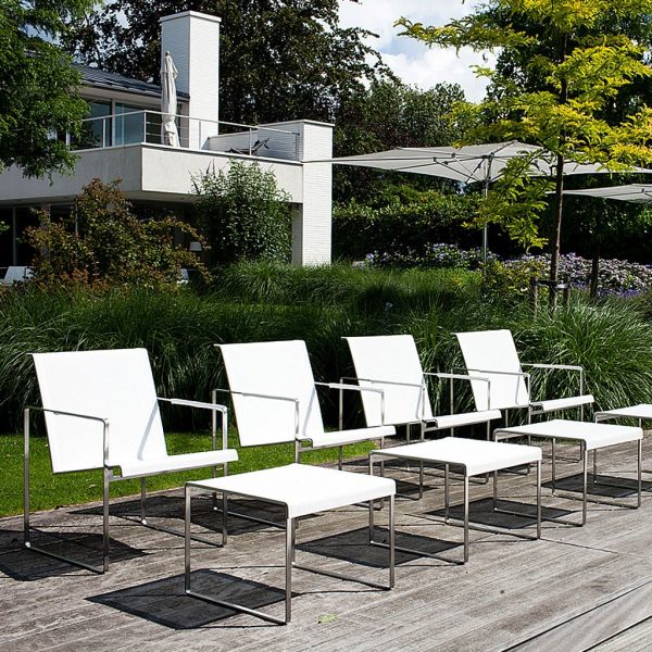 Image of row of 4 Poltrona modern outdoor relax chairs and foot stools by FueraDentro, shown on sunny wooden decking with plants and contemporary house in the background