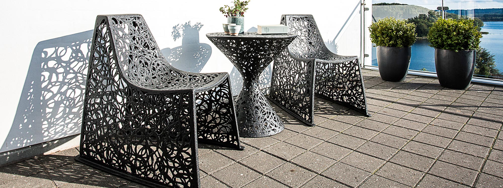 Image of pair of black X chairs next to Race table on wooden decked terrace by Unknown Nordic furniture