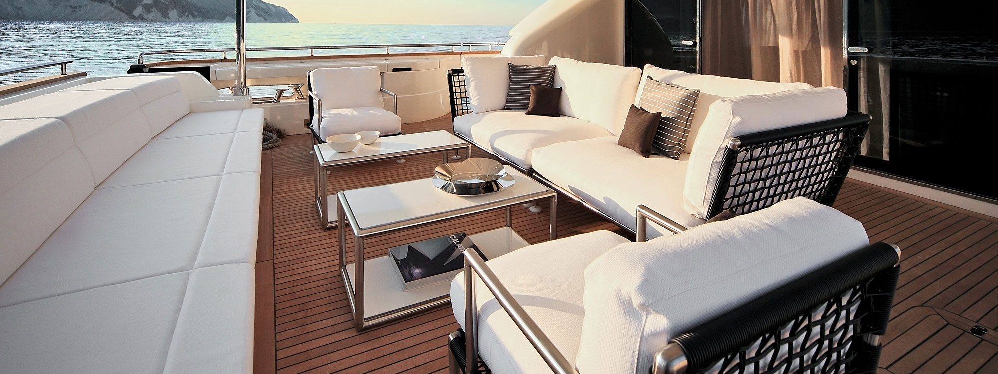 Image of Coro Nest garden sofa and lounge chairs with tubular stainless steel frames and black PVC cord arms and backs, shown on teak aft deck of superyacht
