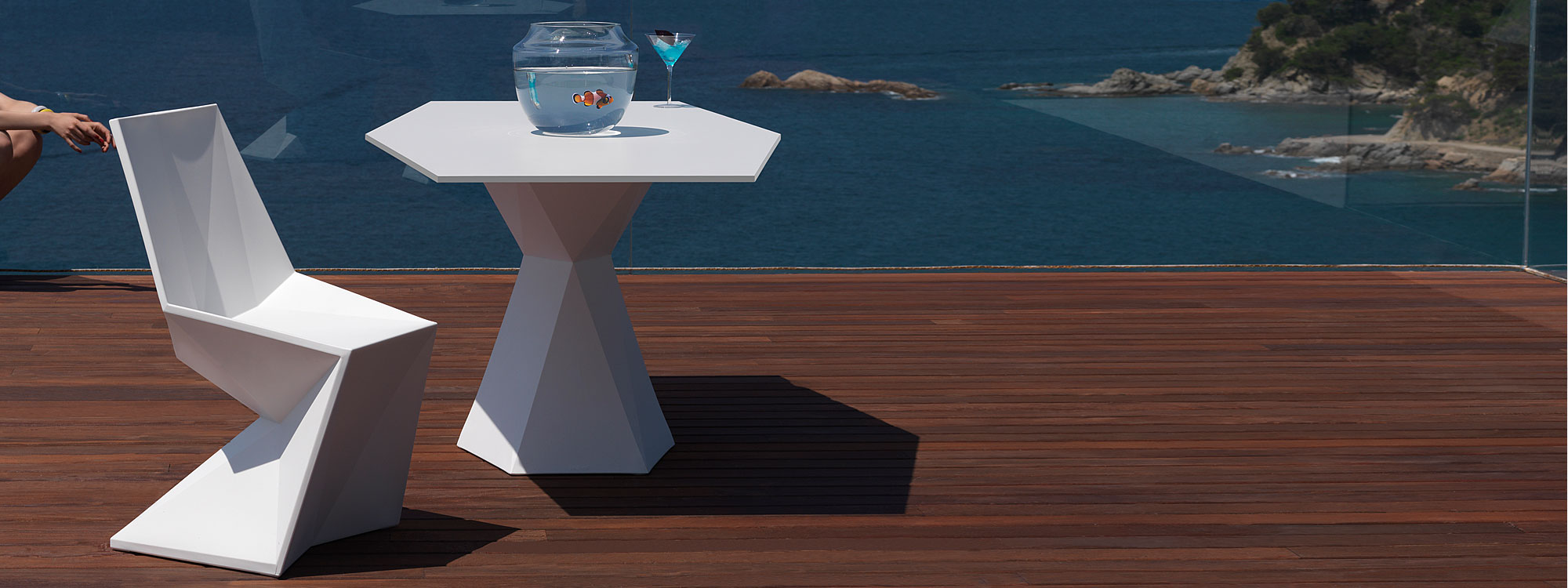Image of small hexagonal white Vertex table and chair by Vondom on balcony overlooking the sea