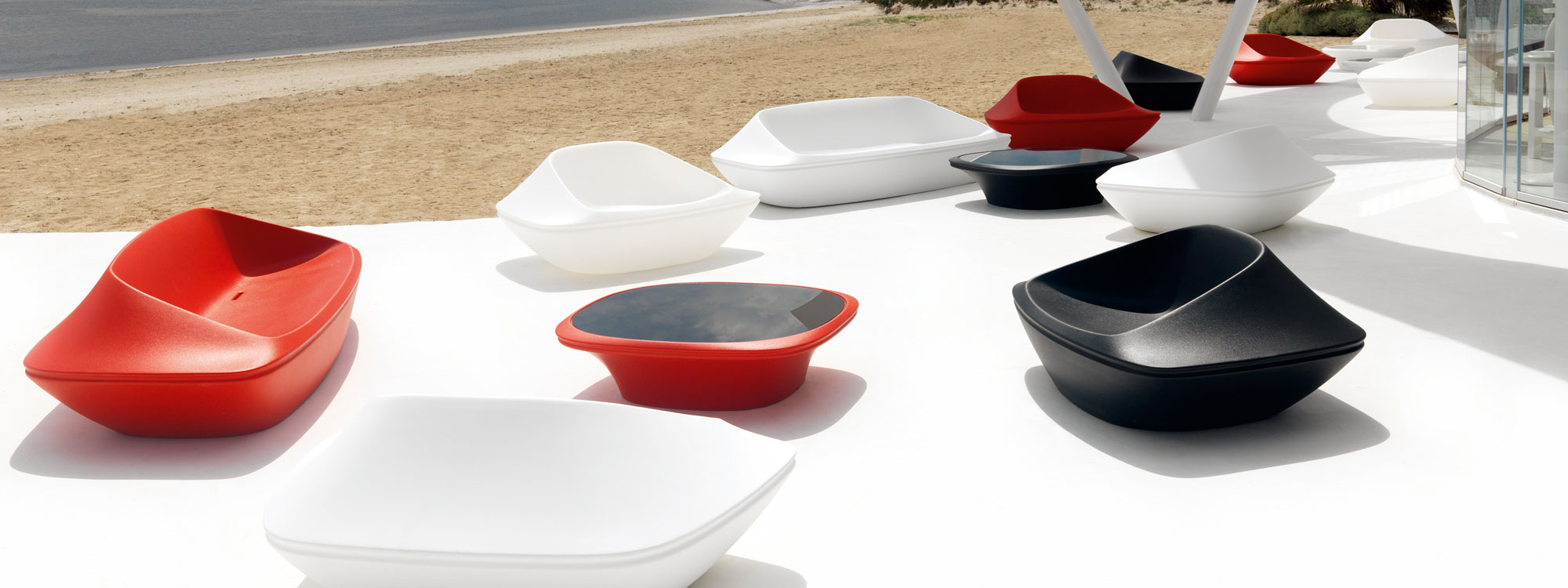 Image of different coloured Vondom UFO futuristic garden furniture on white terrace with sand and sea in the background