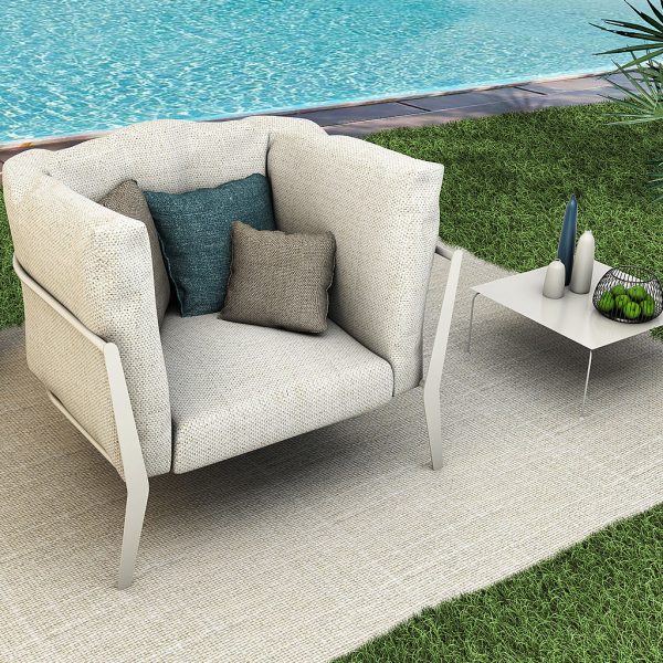Image of Coro Clea contemporary outdoor lounge chair with taupe frame and taupe cushions, shown on outdoor rug on grassy poolside