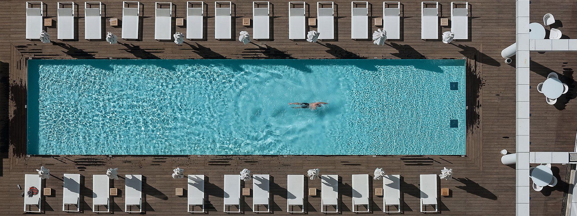 Image of aerial view of Israeli hotel swimming pool with multiple Siesta modern sunbeds on either side of the pool