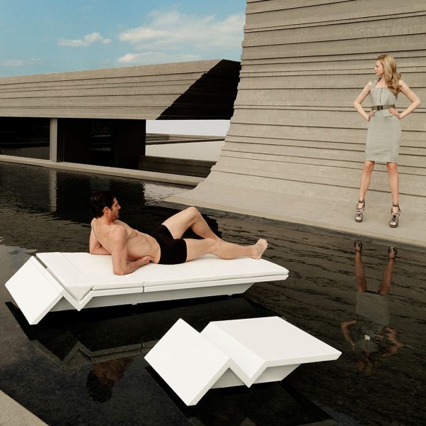 Image of man lying on Vondom Rest modern white sun lounger, whilst talking to woman stood to the side