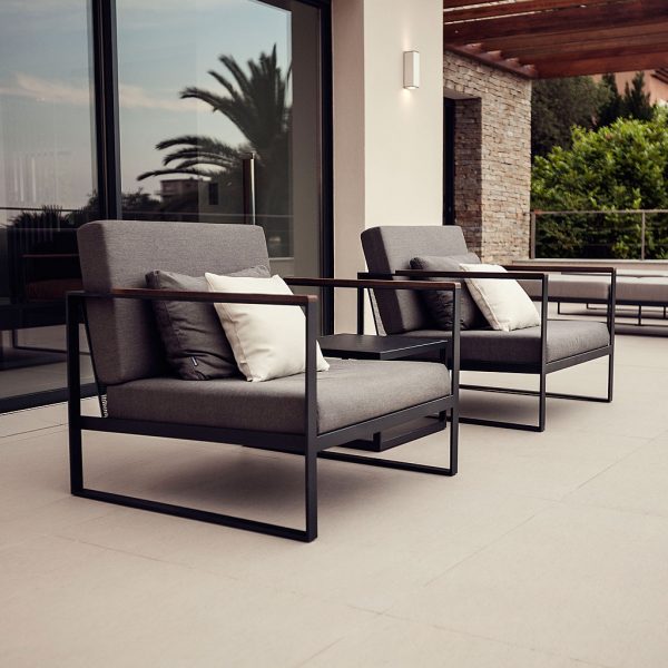 Image of pair of Roshults Garden Easy relax chairs on terrace, with floor to ceiling window in background reflecting the fronds of a palm tree