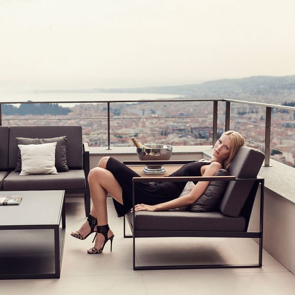 Image of woman relaxing in Roshults Garden Easy outdoor lounge furniture on terrace with city in background