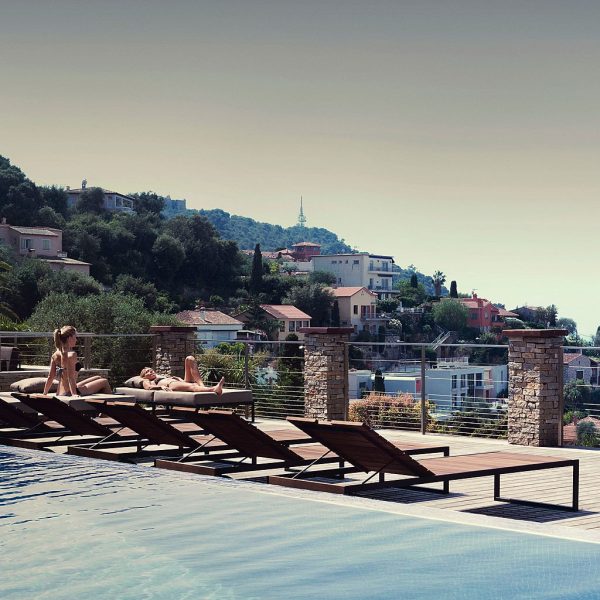 Image of row of Roshults teak and anthracite sun loungers alongside swimming pool, with hill dotted with villas and woodland in the background