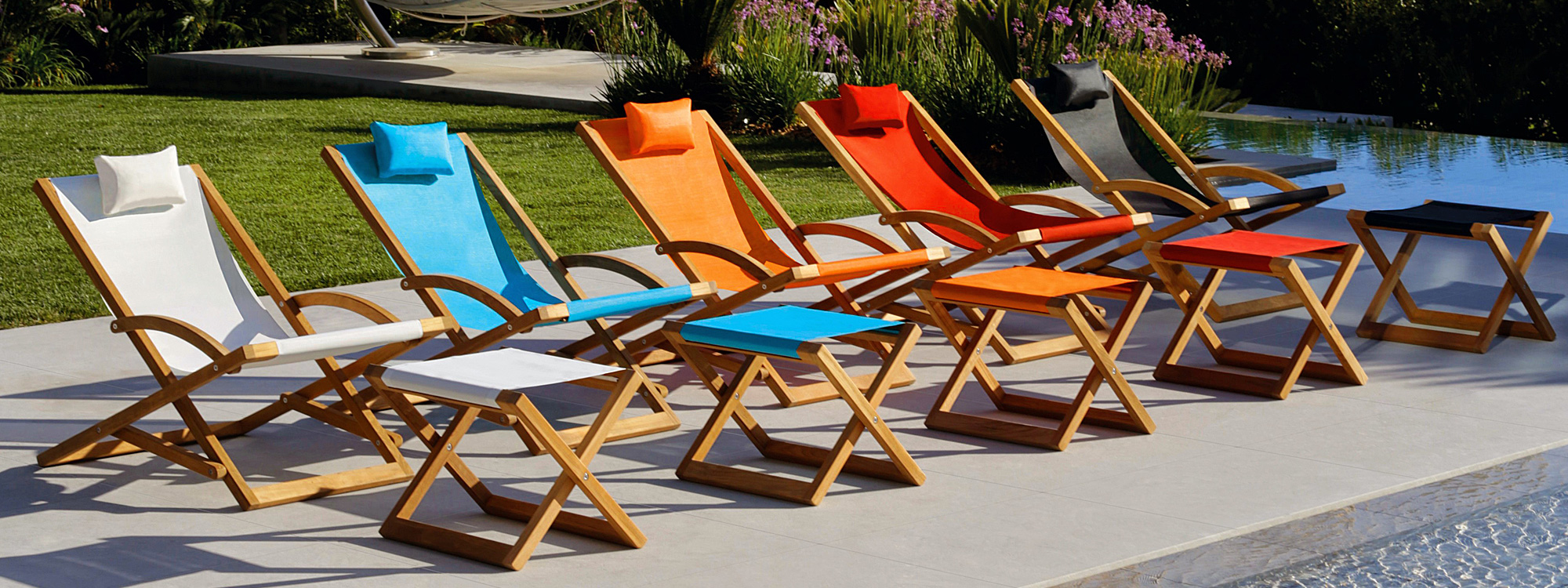 Image of line of Beacher deck chairs in multiple colors by Royal Botania, alongside swimming pool