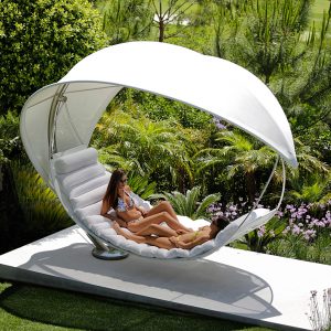 Image of couple lying in white Wave hammock by Royal Botania surrounded by verdant tropical planting