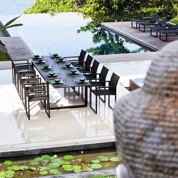 Image of Royal Botania Ninix extending garden table & chairs in front of horizon swimming pool in tropical surroundings