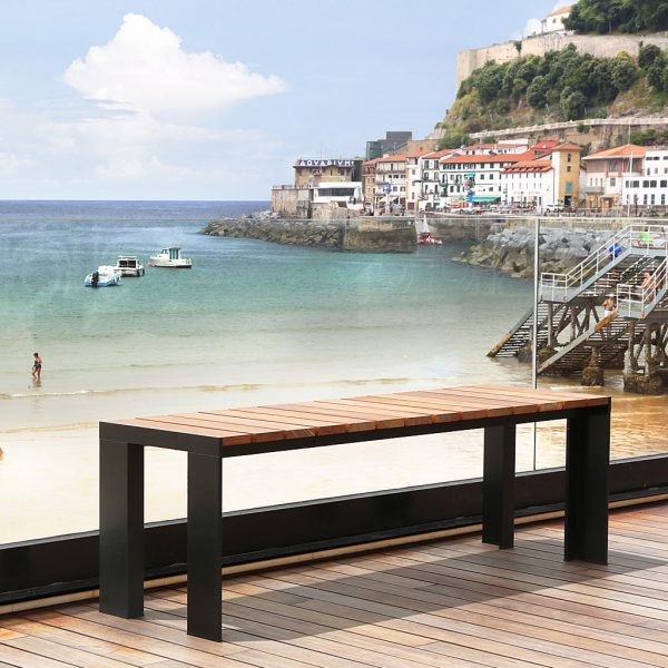 Image of Stua Deneb modern black garden table with slatted teak top, on wooden decked balcony with seaside scene in the background