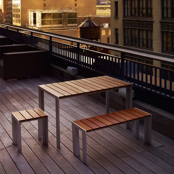 Image of Stua linear garden table and bench seats in anodised aluminium with teak surfaces, with city rooftops in the background