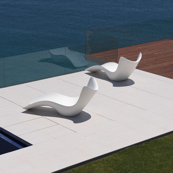 Image of pair of white Surf modern garden chaise longue by Vondom on sunny seaside terrace
