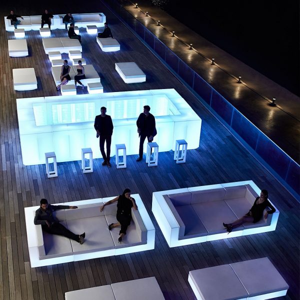 Nighttime image of illuminated Vondom Vela bar counter and outdoor lounge furniture