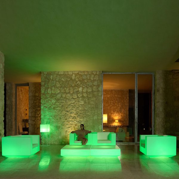 Nighttime image of illuminated green Vela garden sofas by Vondom